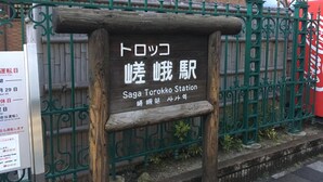 A wooden signboard with Japanese text and English translation for "Saga Torokko Station".