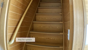 A wooden staircase with a handrail, leading to an upper floor.