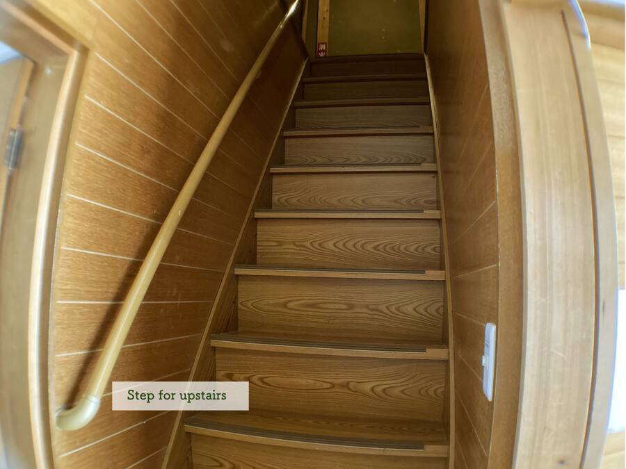 A wooden staircase with a handrail, leading to an upper floor.