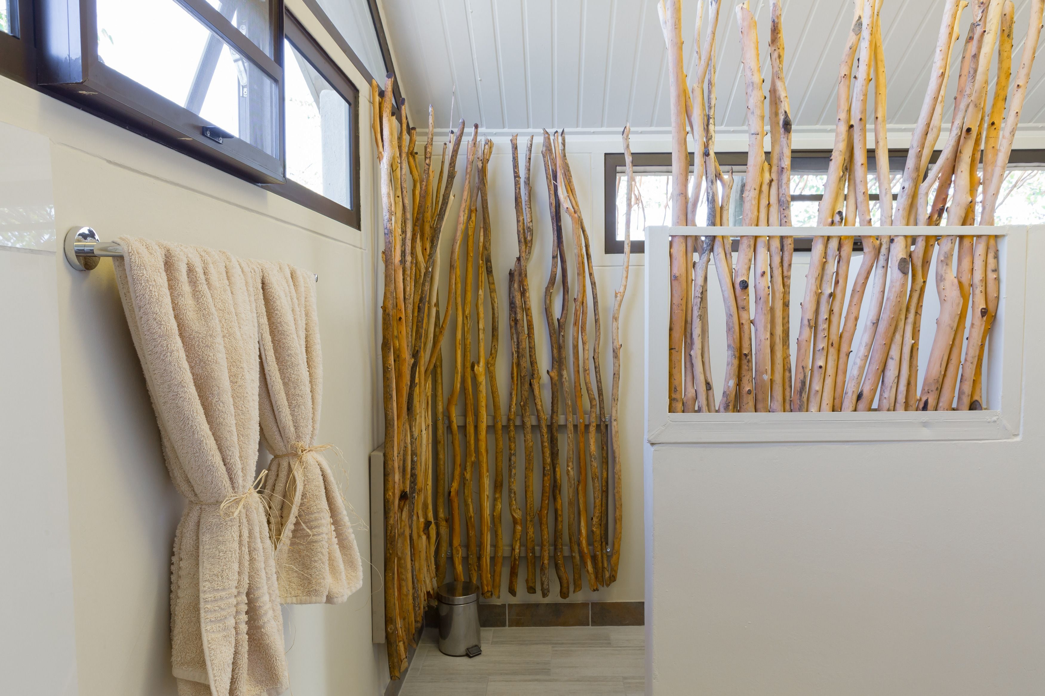 Ein Badezimmer mit Handtuchhalter, Fenster und einer Wandleiste aus Holz.
