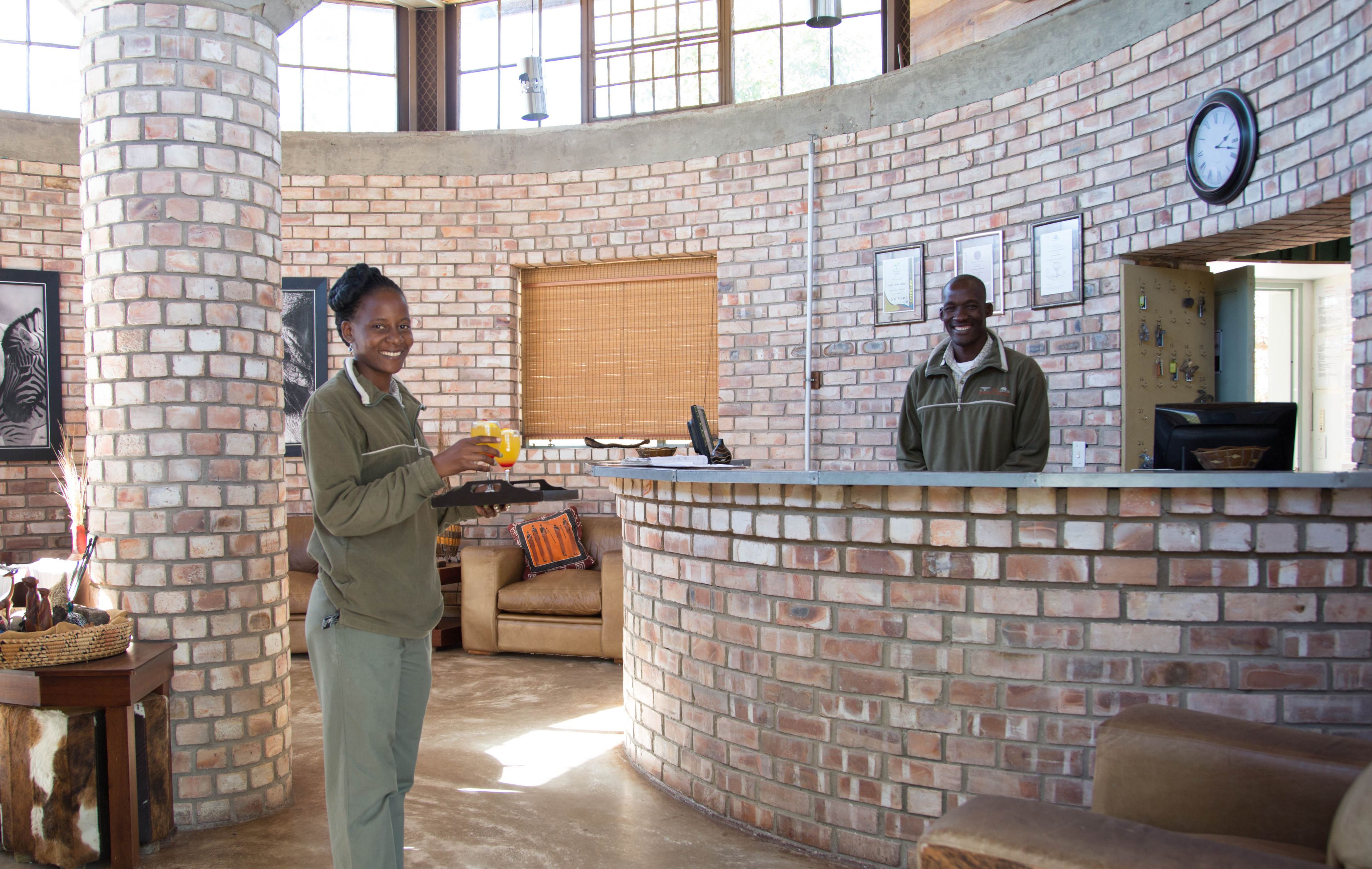A reception area with a brick wall, a clock, and a counter.