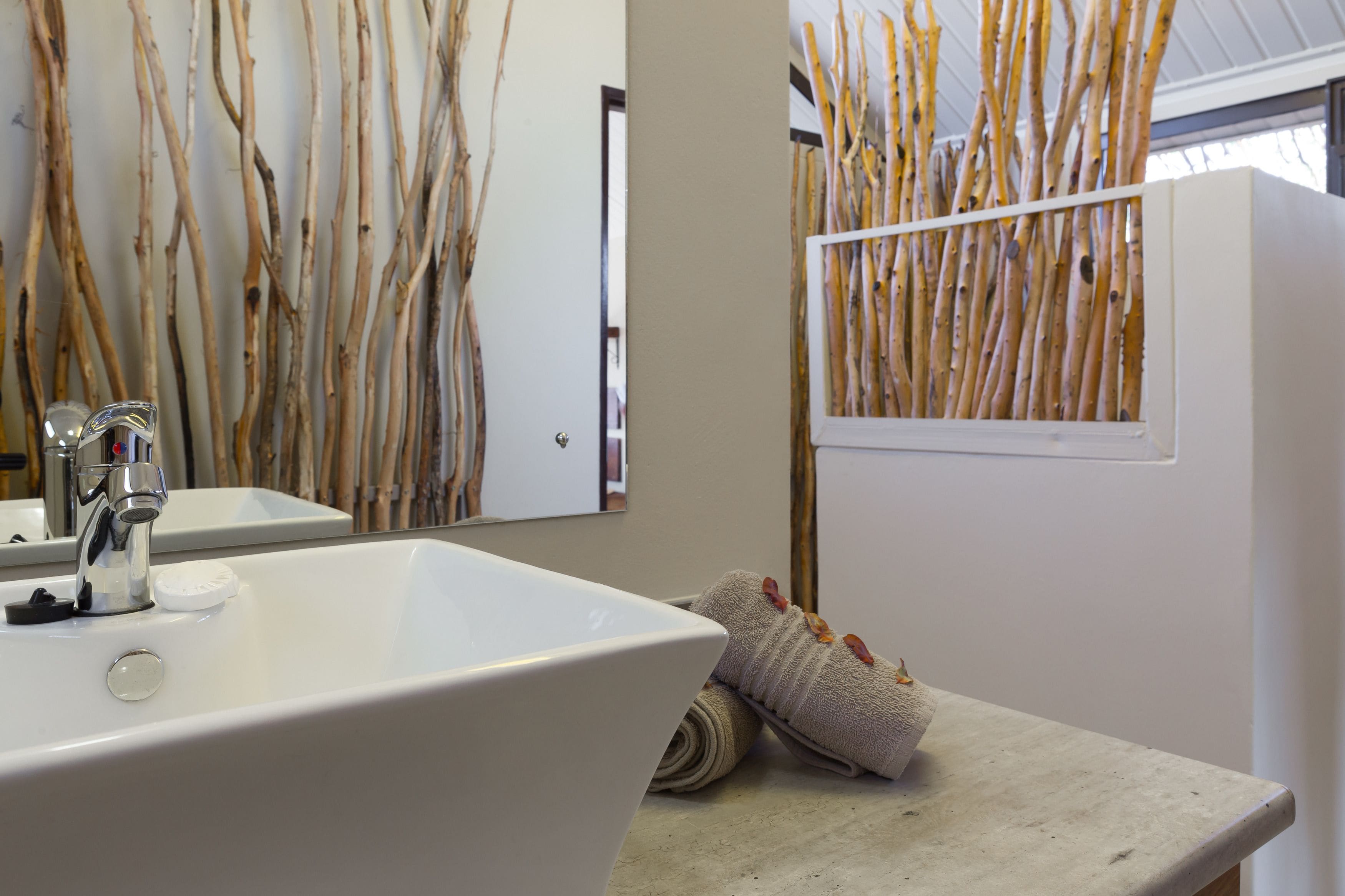 A bathroom with a white sink, a mirror, and a towel rack with a towel.