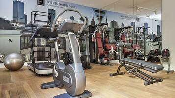 Un gimnasio con máquinas de cardio, equipo de levantamiento de pesas y un mural con vistas a la ciudad.