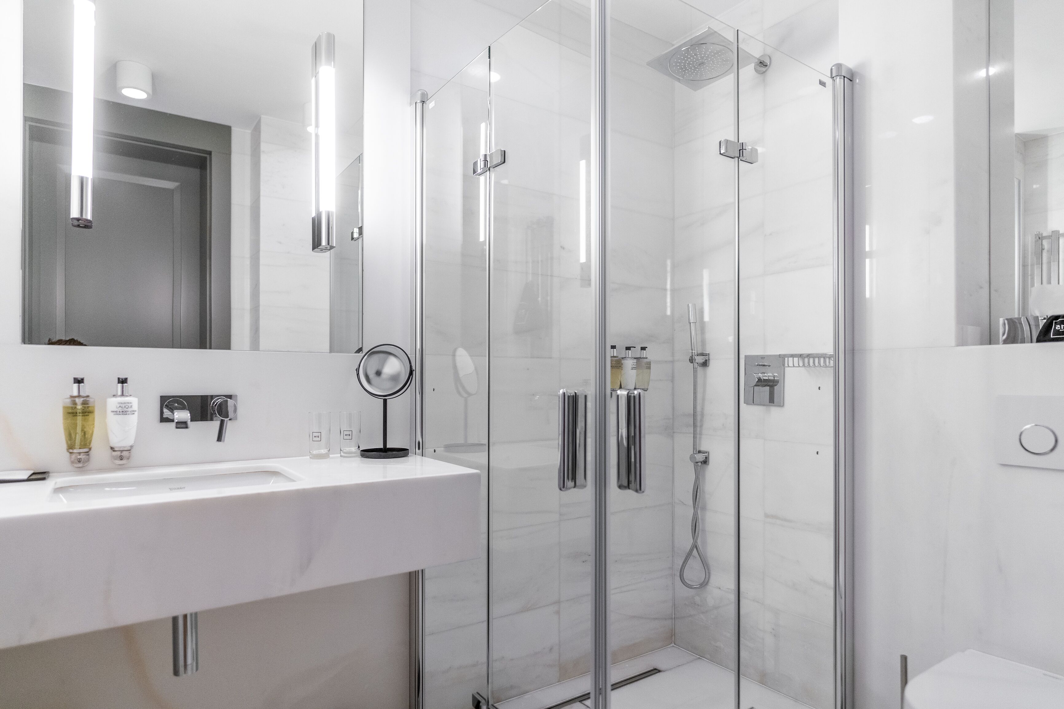 Un baño moderno con ducha de vidrio, lavabo blanco y espejo.