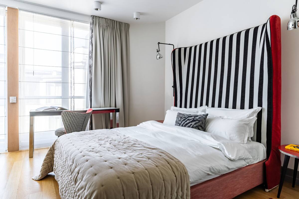 A neatly arranged hotel room with a large bed, a desk, and a chair.