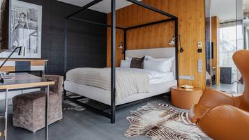 A modern bedroom with a four-poster bed, a desk, and a leather chair.