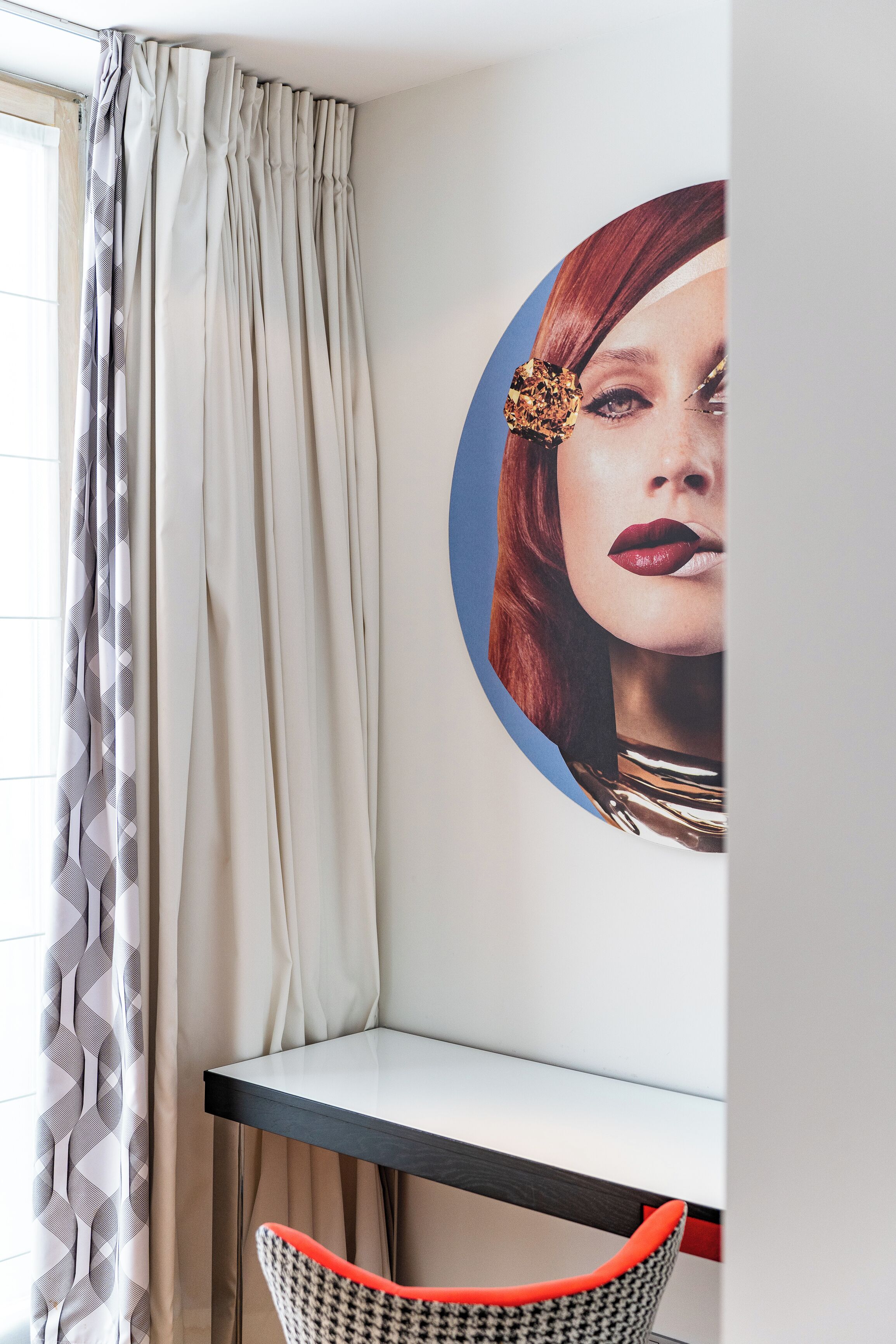 Una esquina de habitación con una mesa, una silla y un cuadro circular en la pared.