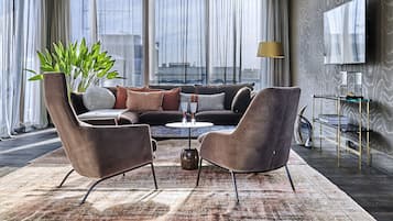 A modern living room with a sofa set, two armchairs, a coffee table, and a large plant.