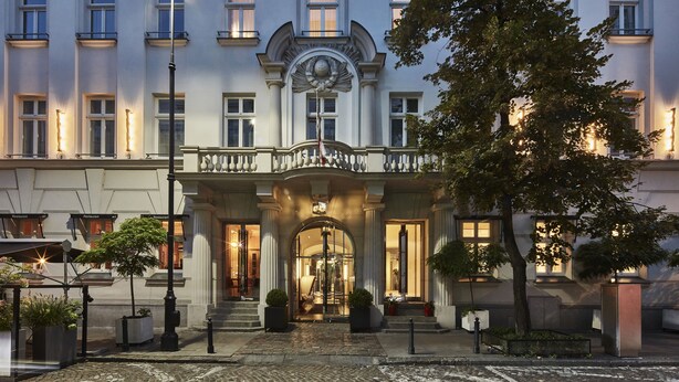 A hotel entrance with a grand archway, columns, and a balcony.