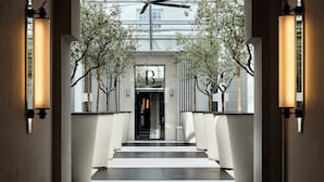 A modern hotel lobby with a central staircase, a reception desk, and a large letter 'B' sign.