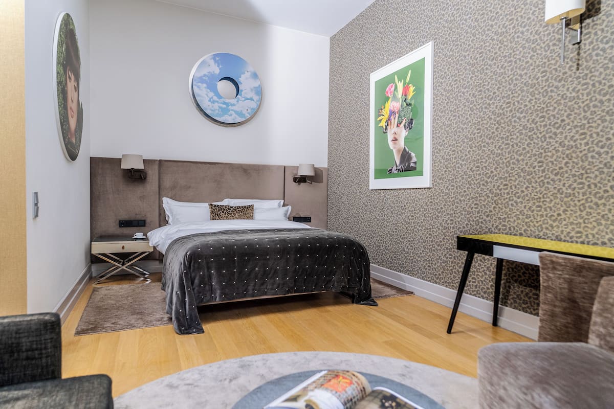 A modern bedroom with a bed, bedside tables, a desk, and a chair.