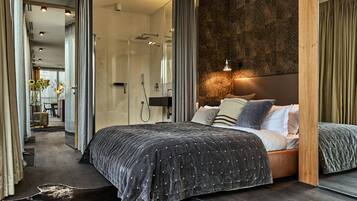 A modern bedroom with a large bed, a wooden headboard, and a stone accent wall.