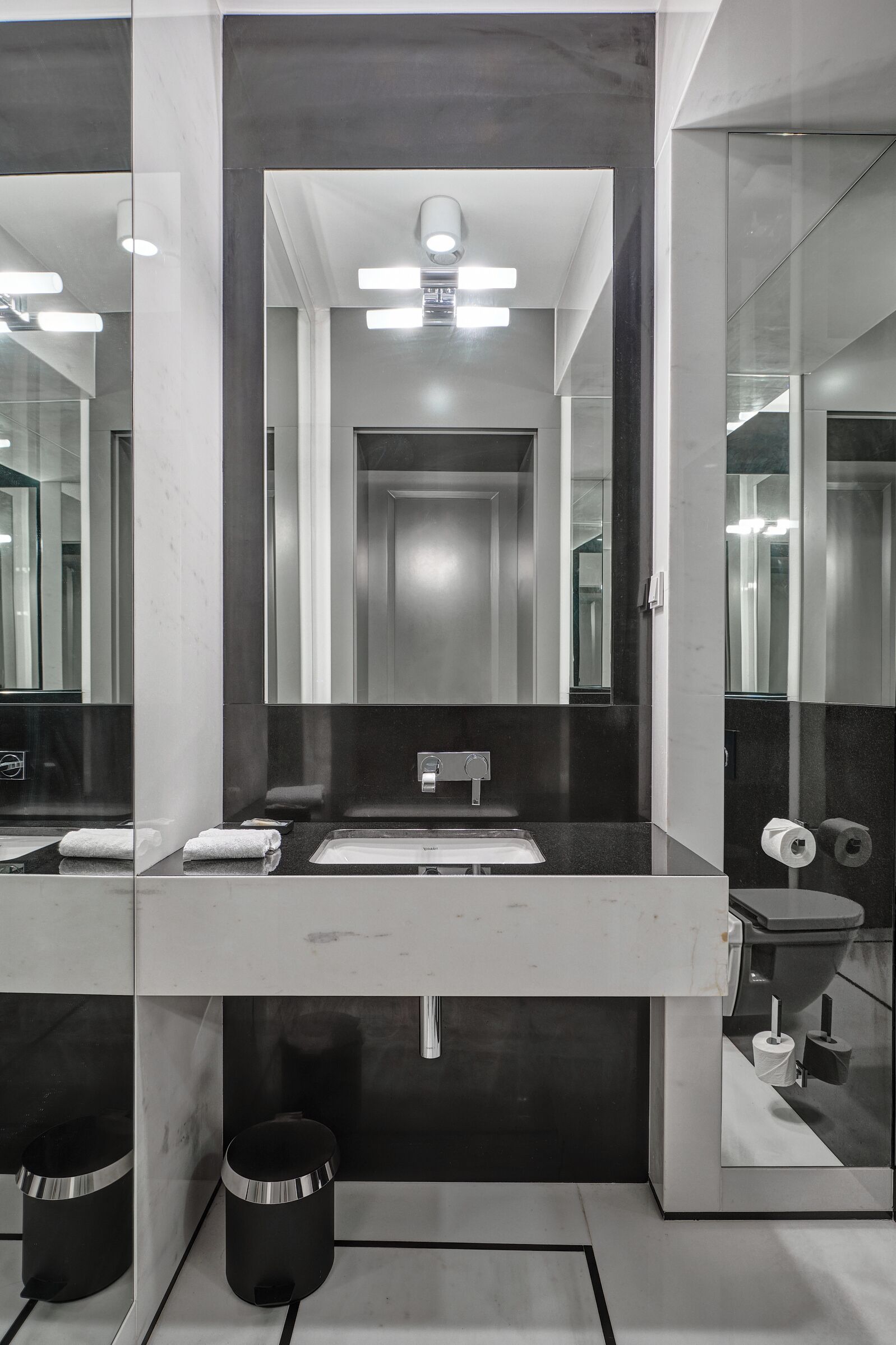 Un bagno moderno con uno specchio grande, un lavandino e due cestini.