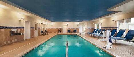 Une piscine intérieure avec des couloirs bien délimités, un vestiaire et des chaises longues.