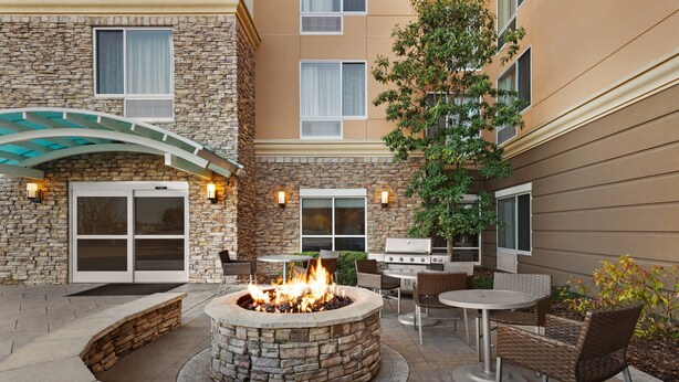 Une terrasse extérieure avec un foyer en pierre, des tables et des chaises pour les repas.
