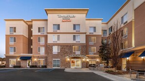 Un hôtel TownePlace Suites doté d’une façade en pierre, de plusieurs étages et d’un parking.