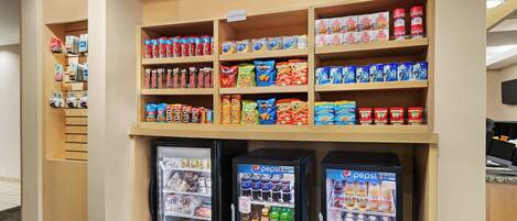 Esposizione di snack e bevande con diversi prodotti confezionati, tra cui Pepsi, e un cartello con la scritta 'In caso di necessità'.
