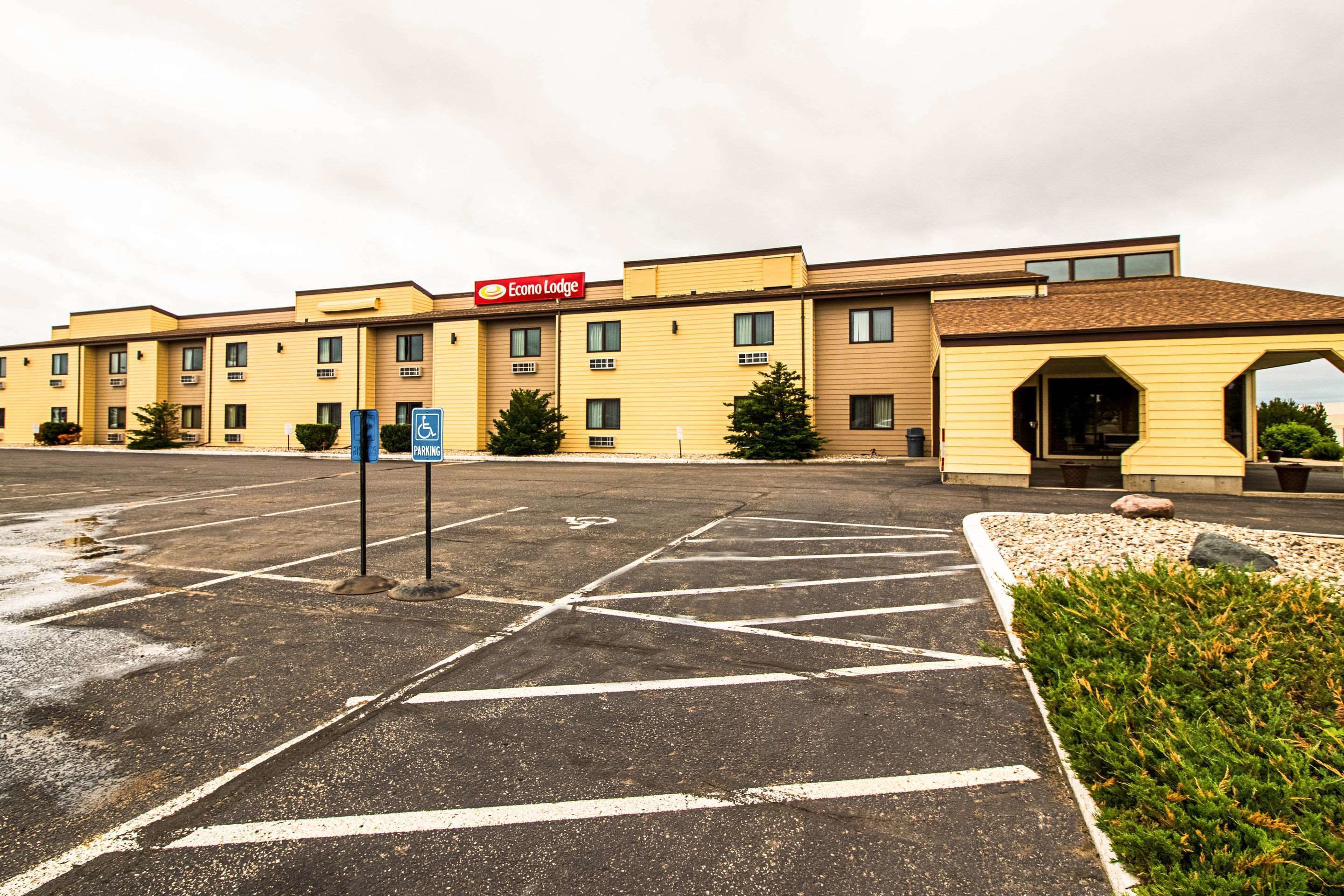 A parking lot with a handicap parking sign, a sign for Econo Lodge, and a building with a brown roof and beige walls.