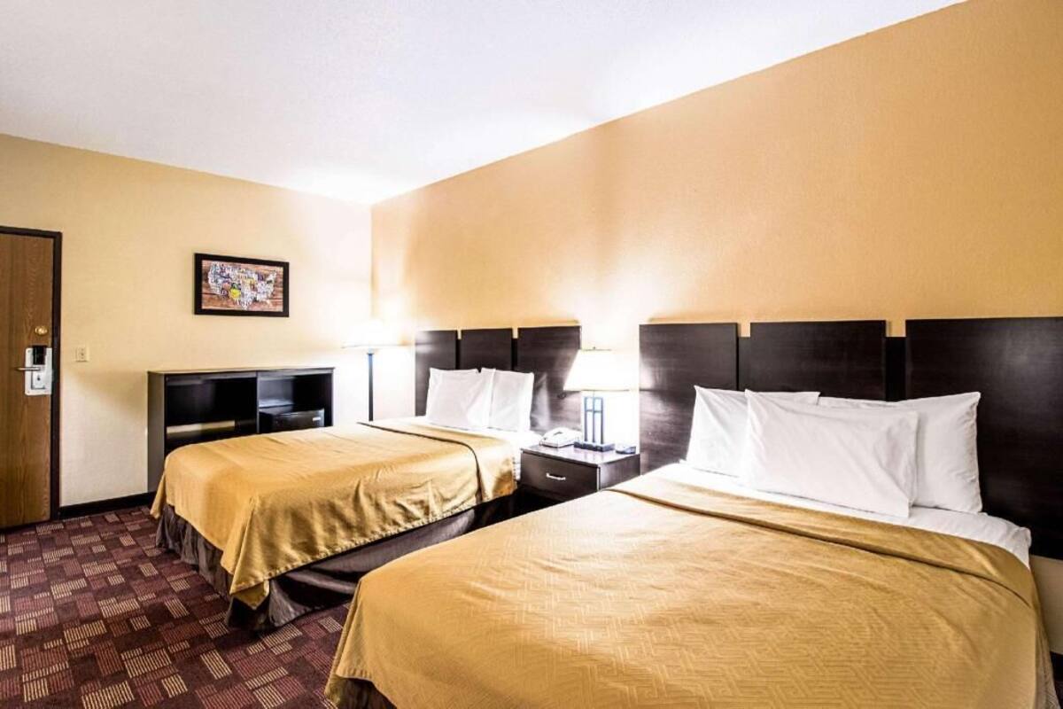 A hotel room with two beds, a TV, a desk, and a picture on the wall.