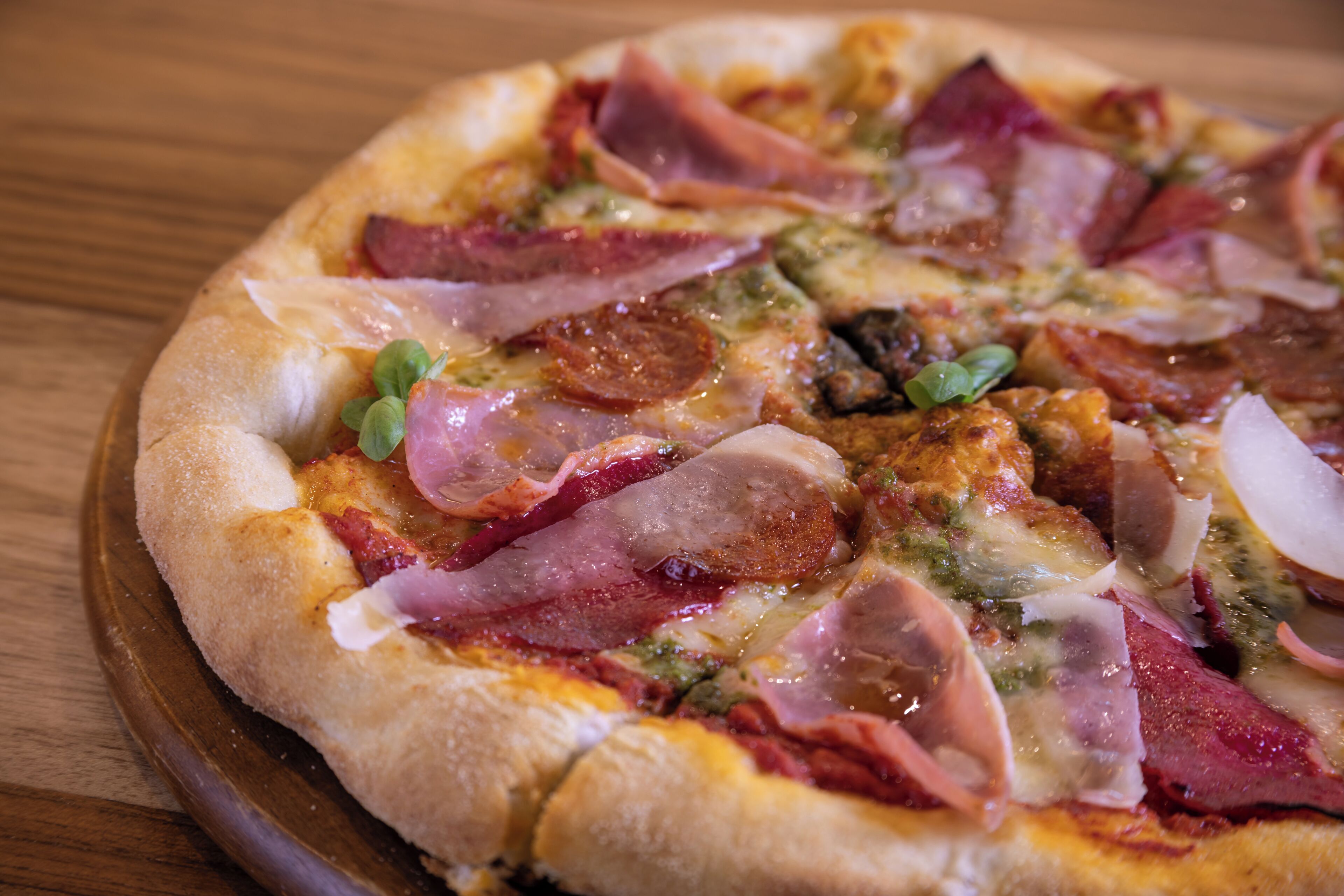 En pizza med forskellige toppings på et træbord.