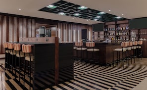 Een bar met een geruite vloer, houten lambrisering en een bar met krukken.