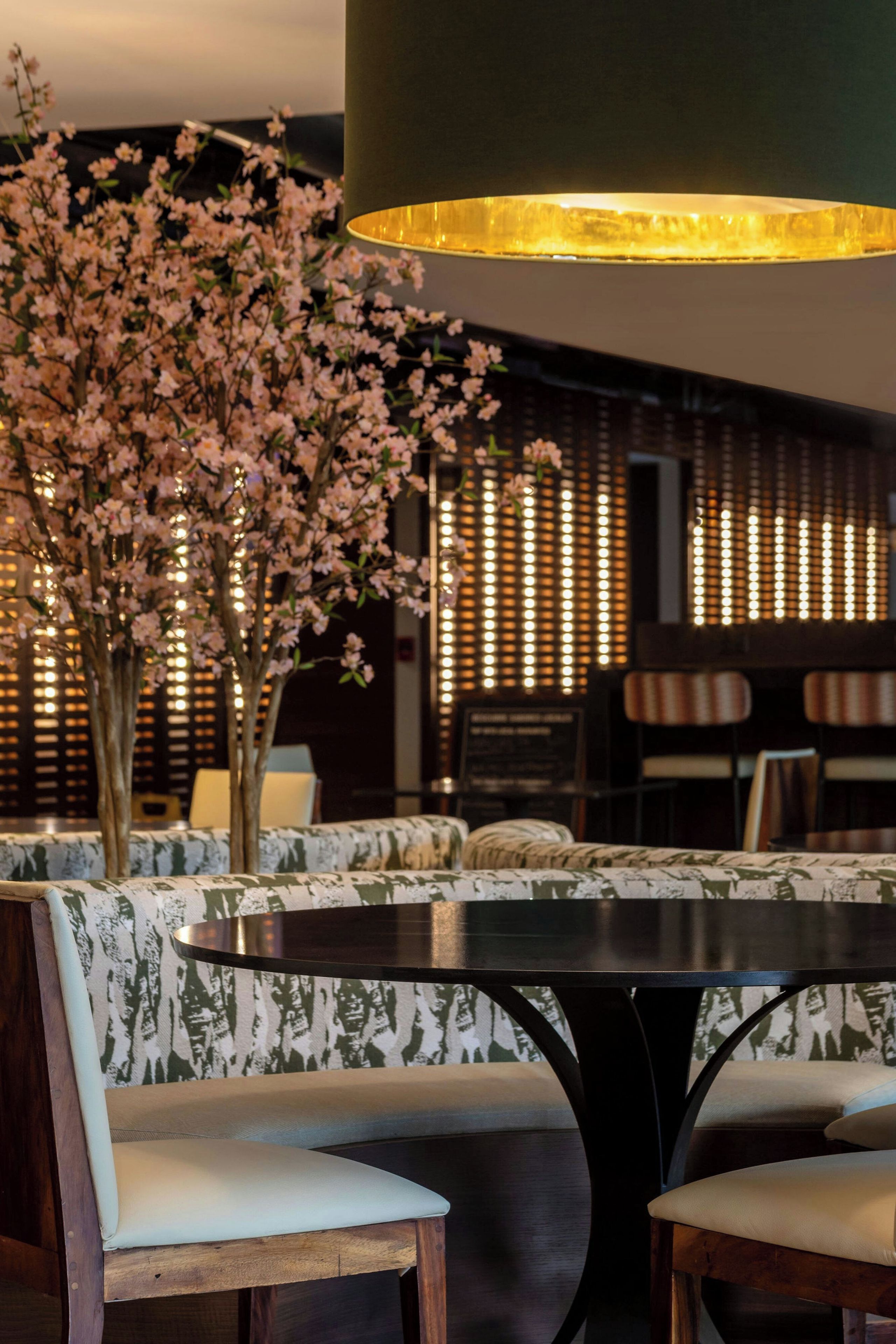 A dining area with a round table, cushioned chairs, and a decorative floral arrangement.
