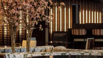 Un comedor con una mesa redonda, sillas acolchadas y un arreglo floral decorativo.