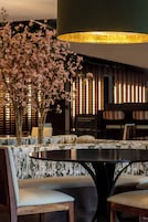 A dining area with a round table, cushioned chairs, and a decorative floral arrangement.