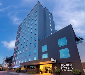 A modern hotel building with a flat facade, multiple windows, and a sign indicating it is a Sheraton hotel.