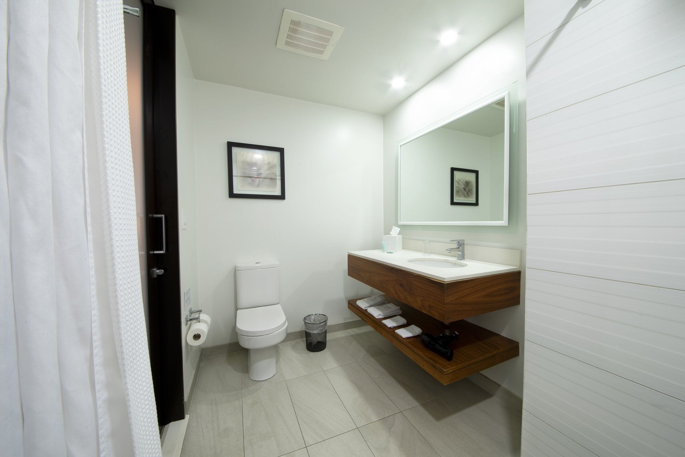 Et moderne badeværelse med toilet, vask og spejl.