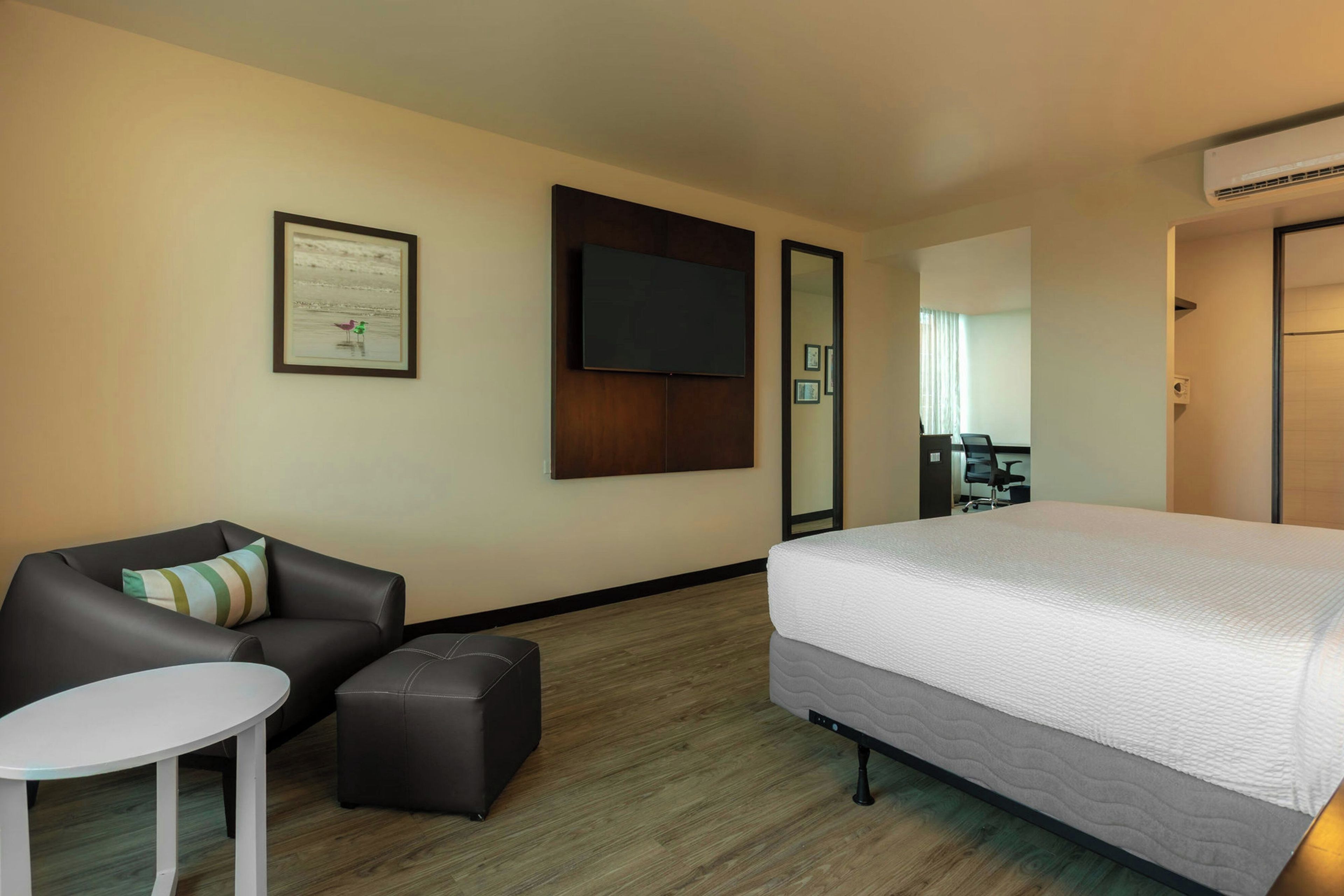 A hotel room with a bed, a sofa, a small table, and a TV.