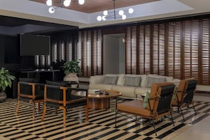 Una sala de estar moderna con un sofá, sillas, una mesa de centro, un televisor y un piso con estampado.