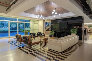 Un interior moderno con piso a cuadros, un sofá, sillas y una escalera que sube a un nivel superior.