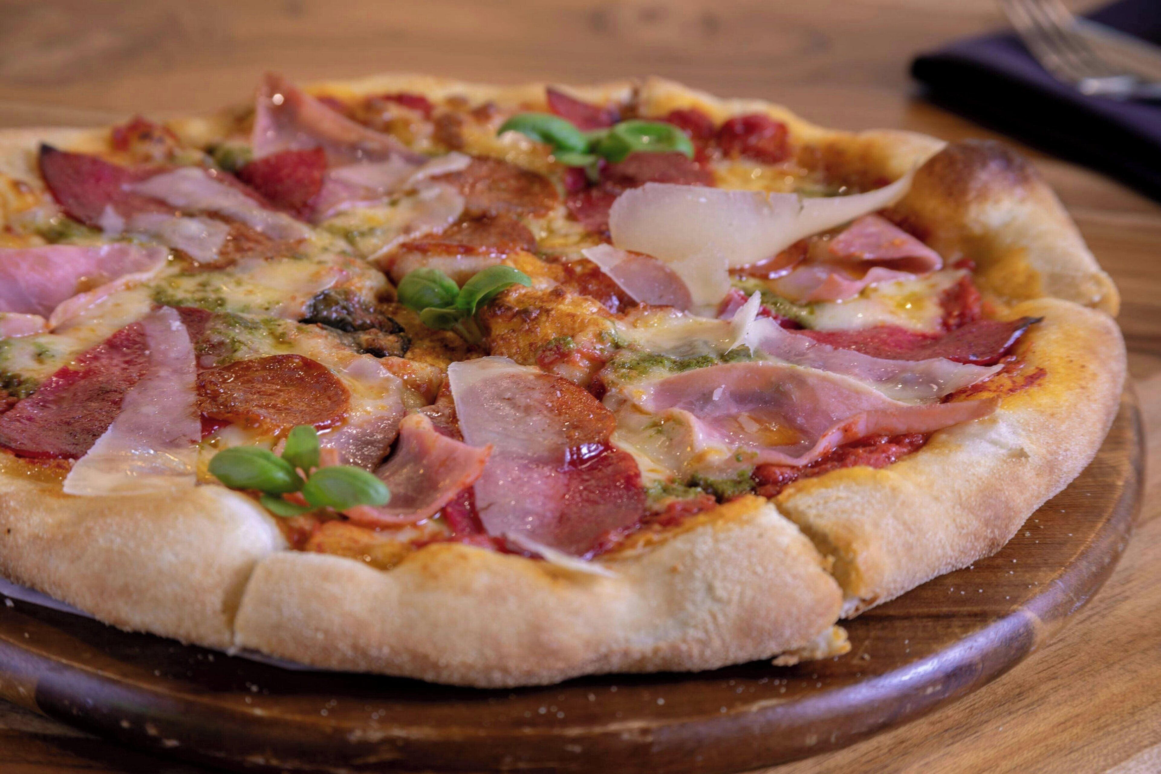 Uma pizza sobre uma tábua de madeira.