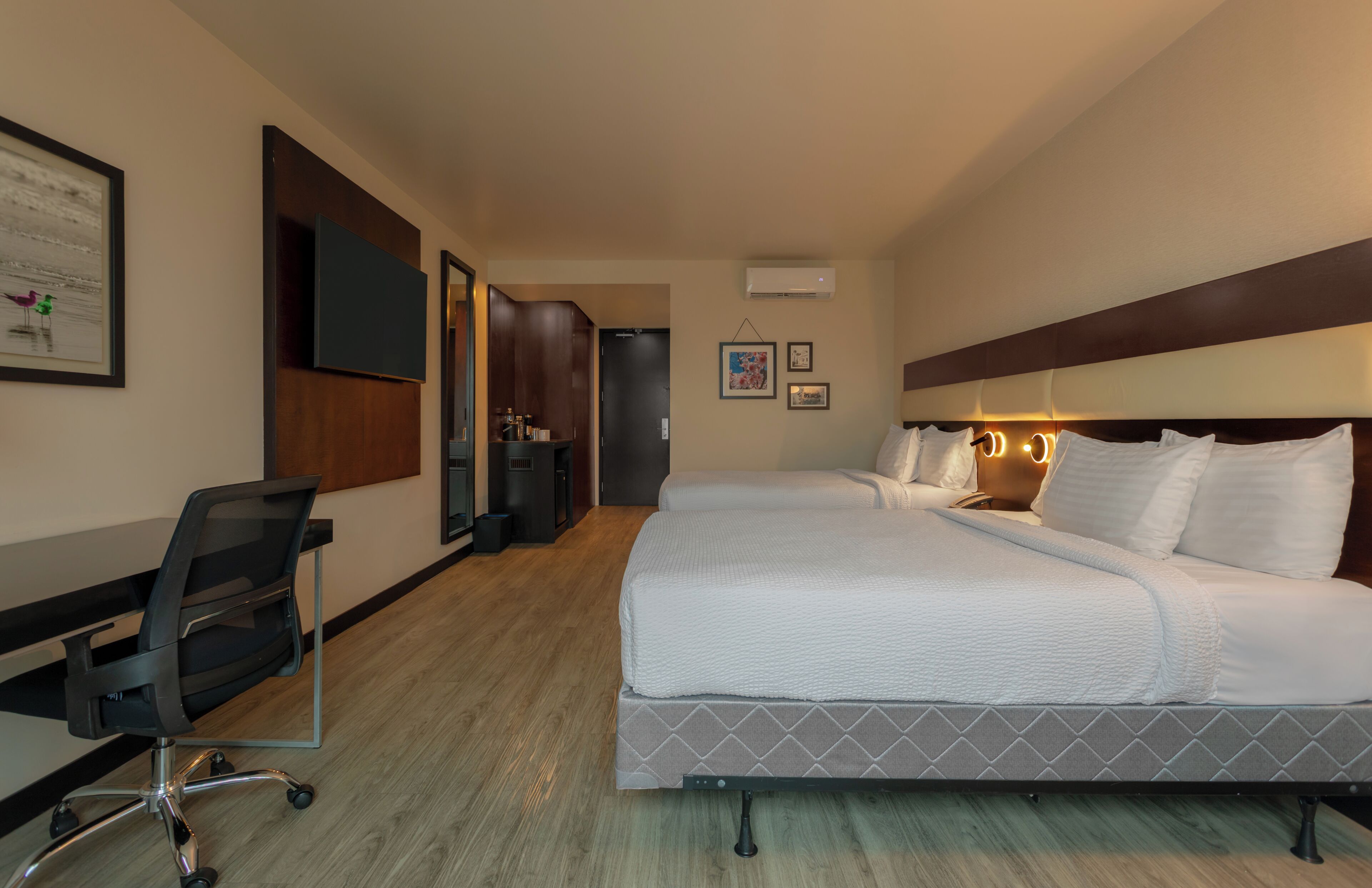 Une chambre d’hôtel avec un lit, un bureau, une chaise, une télévision et une porte.