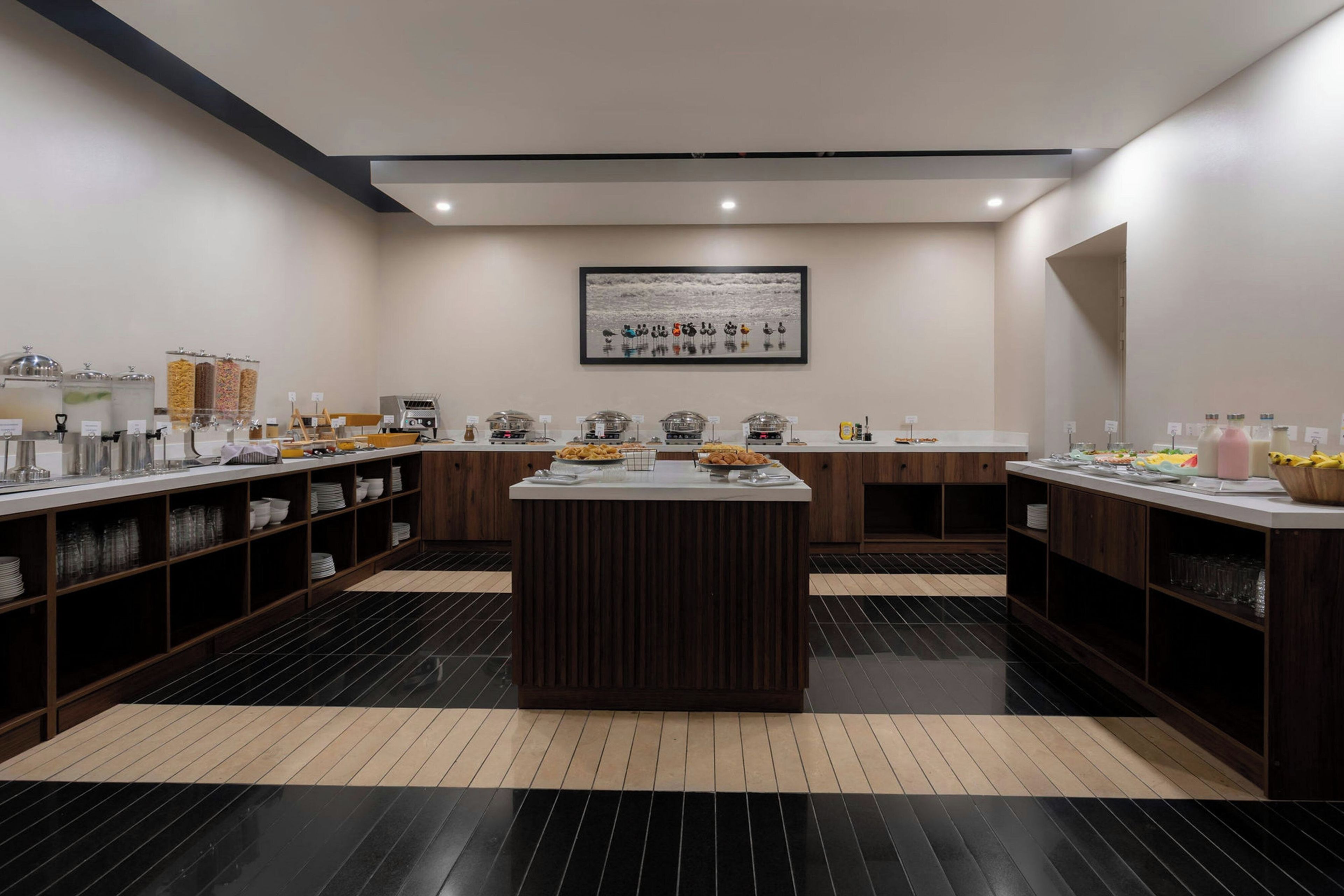A modern kitchen with a central island, equipped with various appliances and a buffet setup.