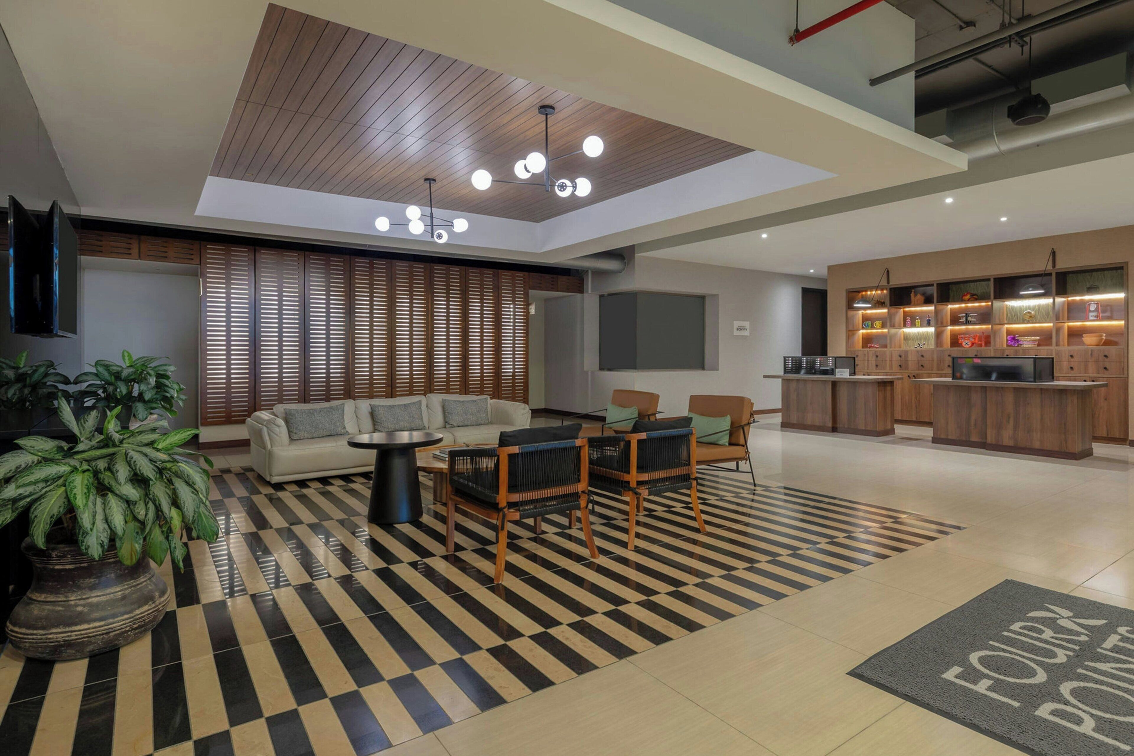 Una sala de estar moderna con sofá, sillones, una mesa de centro y una alfombra estampada.