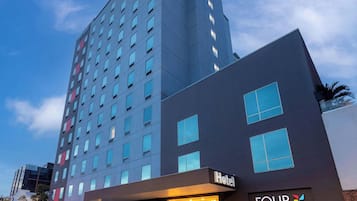 Un hôtel à plusieurs étages au design moderne, reconnaissable à son grand panneau indiquant « Hotel Four Points ».