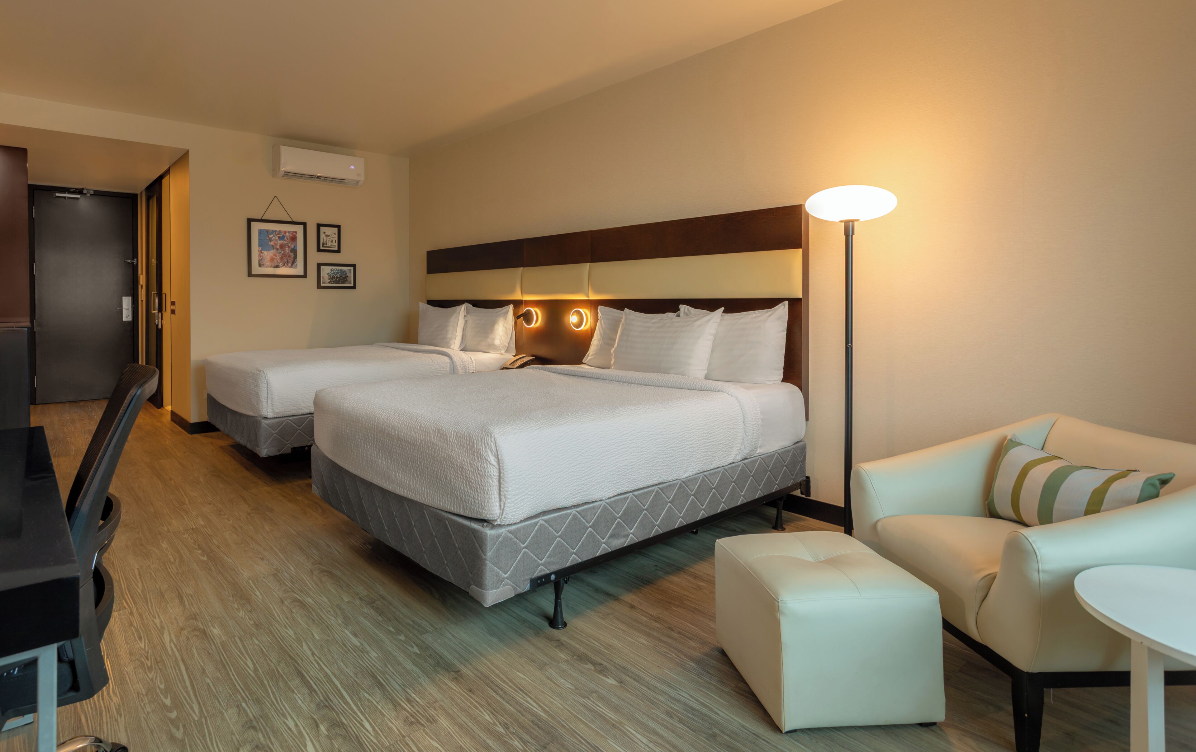 Ein Hotelzimmer mit zwei Betten, einem Schreibtisch, einem Sessel, einem Tisch und einem Sofa.