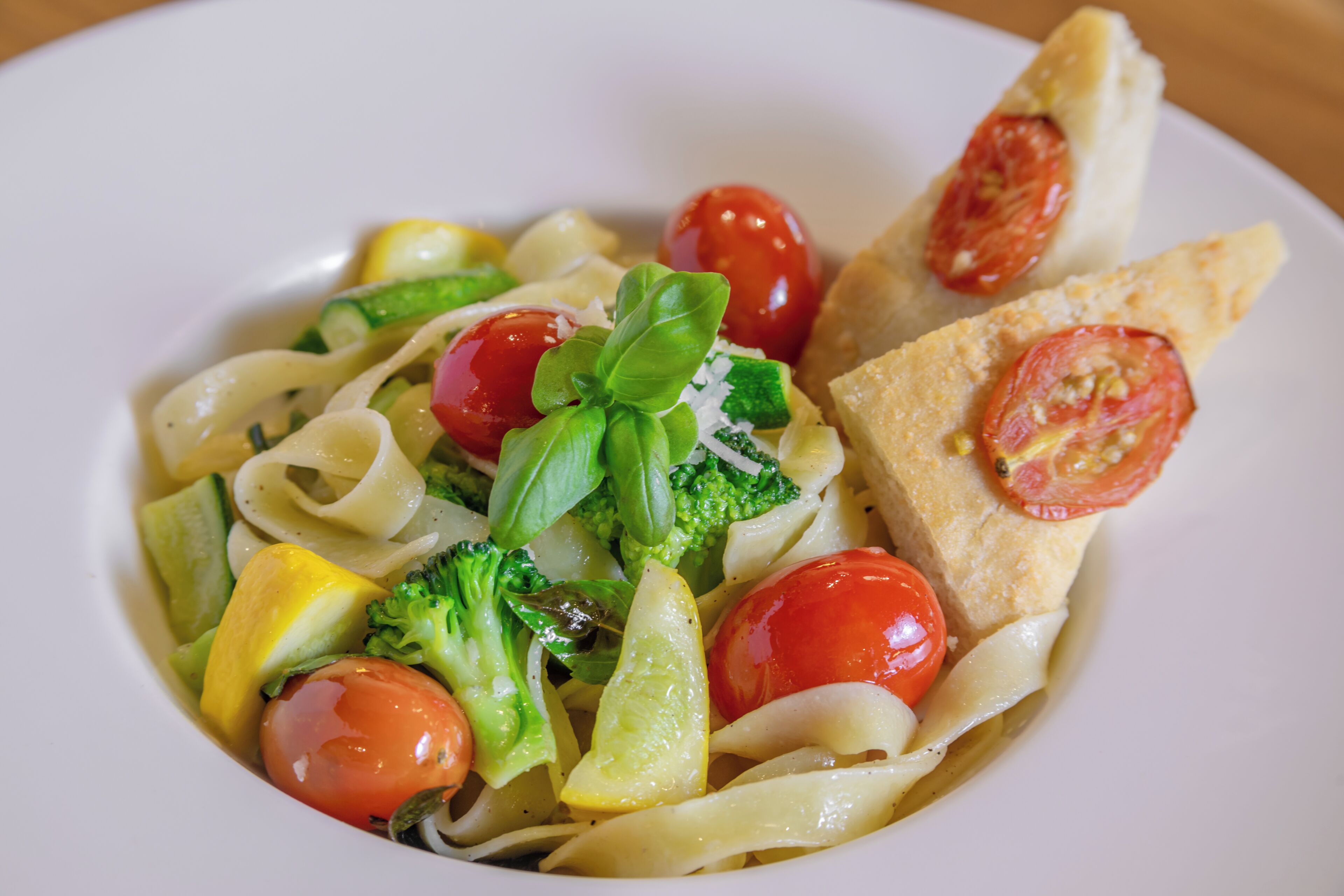 Une assiette de pâtes aux légumes et une tranche de pain.
