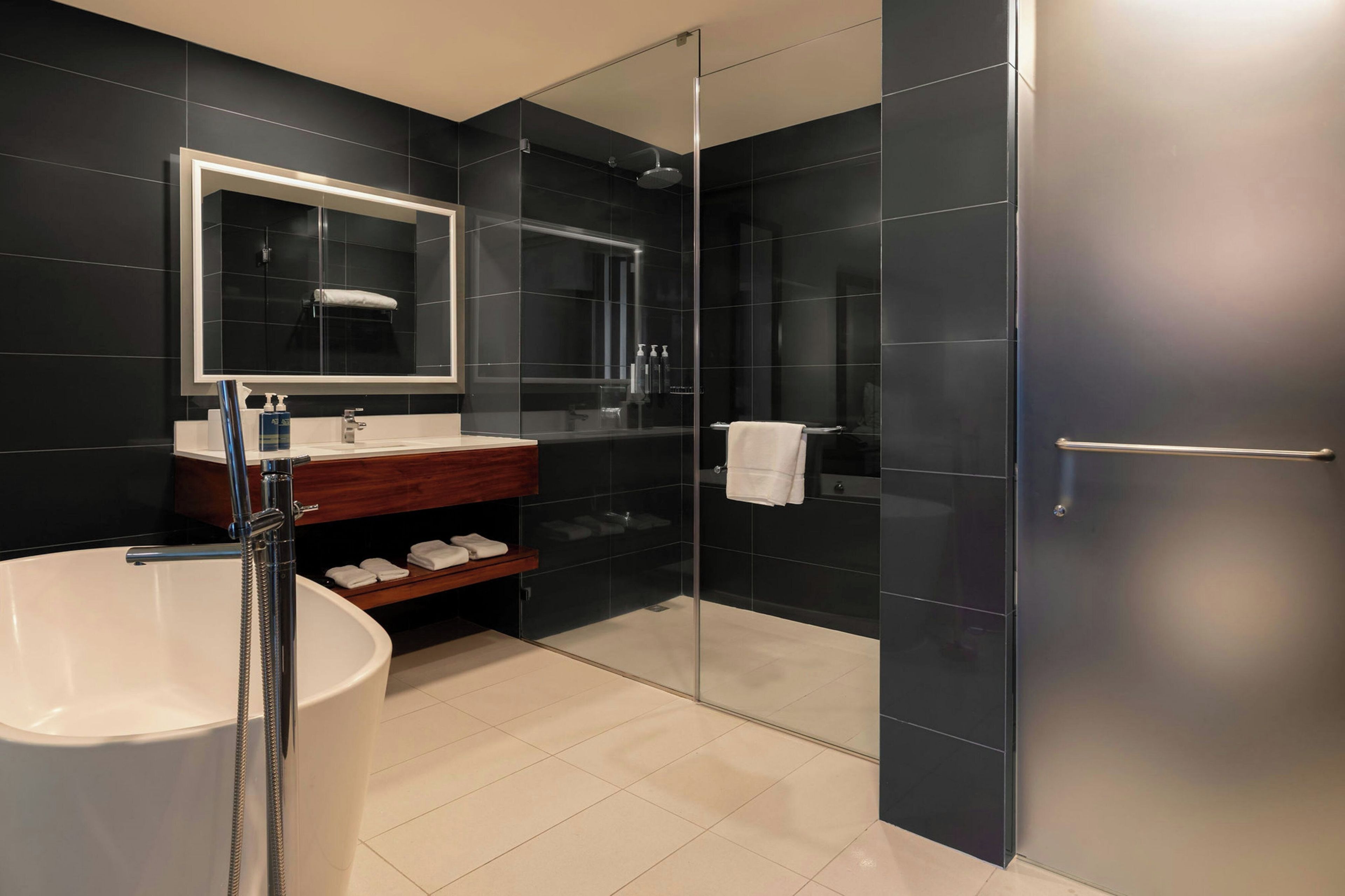 Ein modernes Badezimmer mit einer freistehenden Badewanne, einer Duschkabine und einem Waschtisch mit Spiegel und Waschbecken.