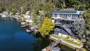 Una proprietà sul lago con un molo, una barca e una casa dotata di pannelli solari.