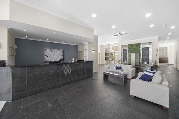 A modern reception area with a dark reception desk, a white sofa, and a coffee table.