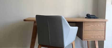 A corner office with a wooden desk, a grey office chair, and a telephone on the desk.
