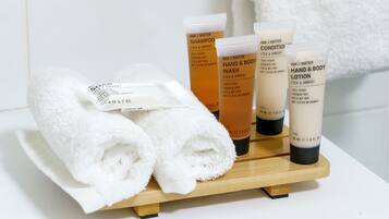 A wooden tray with toiletries including shampoo, conditioner, hand and body wash, and lotion.
