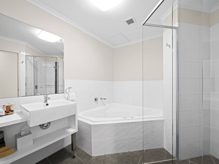 A modern bathroom with a white sink, mirror, and bathtub.