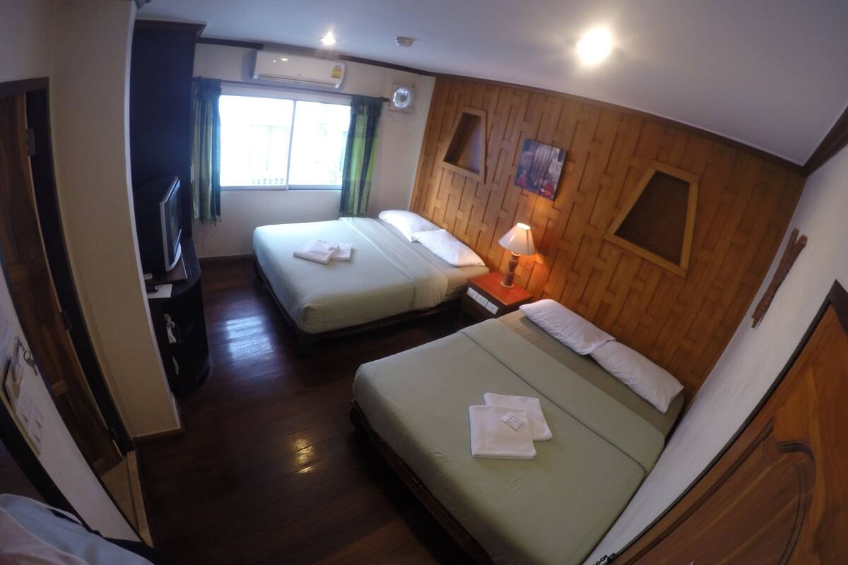 A hotel room with two beds, a TV, and a window with curtains.