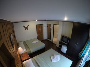 A hotel room with two beds, a TV, a wardrobe, and a mirror.