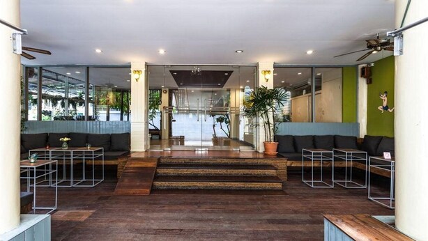 Un vestíbulo moderno con piso de madera, zonas de estar y una escalera que lleva a un nivel superior.