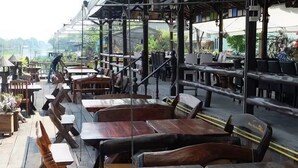 Een terras met houten tafels en banken, waarvan sommige voorzien zijn van stoelen.